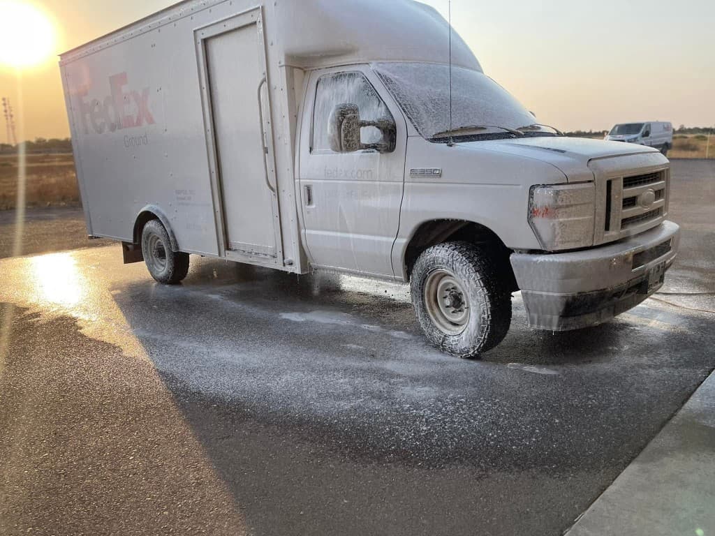 FedEx Ground delivery truck covered in soap foam during fleet washing