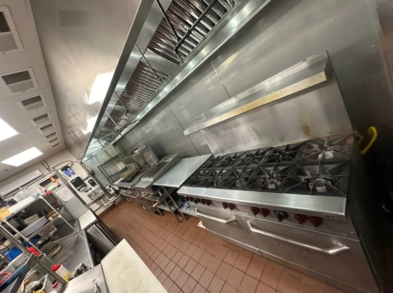 Spotless commercial kitchen exhaust hood and cooking line after professional cleaning